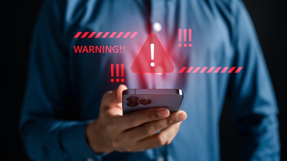 man houdt mobiele telefoon vast die een waarschuwing geeft