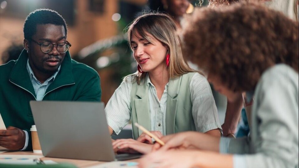 Drie mensen kijken naar een laptop
