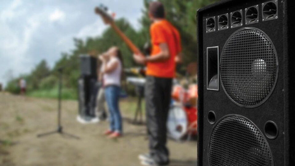 Een bandje speelt buiten, een grote luidspreker staat vooraan in beeld.