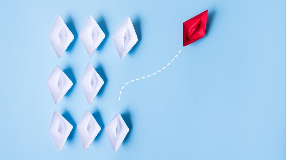 Group of paper ships in one direction and with one individual pointing in the different way, leadership, individuality concepts