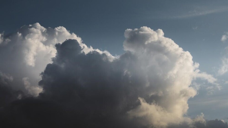 Donkere en lichte wolken in de lucht met een blauwe achtergrond en enkele kleine wolkjes.