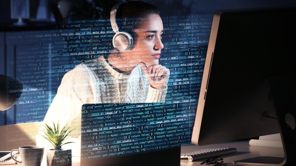 Vrouw achter beeldscherm, computercode is zichtbaar
