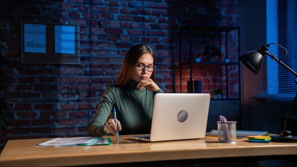 Vrouw in een trendy kantoor denkt na achter laptop