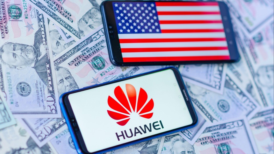 Twee mobiele telefoons. Op de één staat de Amerikaanse vlag, op de ander het logo van Huawei.