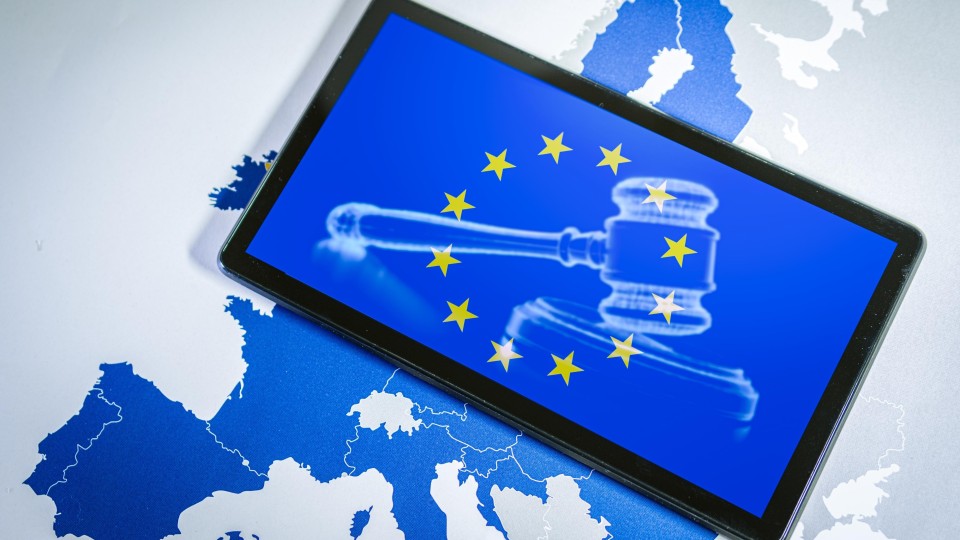 tablet bovenop een Europese kaart met op het beelscherm een voorzittershamer en de sterren van de Europese vlag