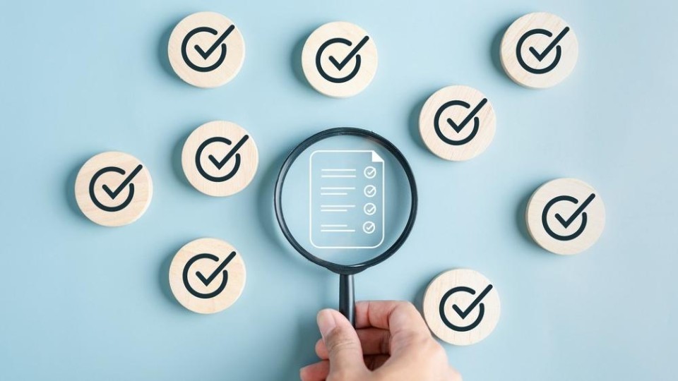 Hand met loep gericht op lijstje met afvinkbare items