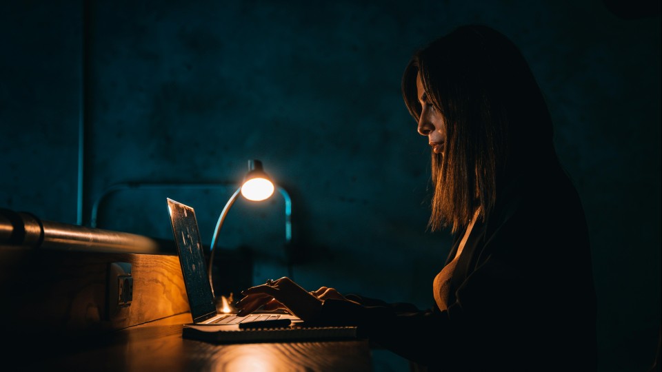 Vrouw in donker werk achter computer hacker