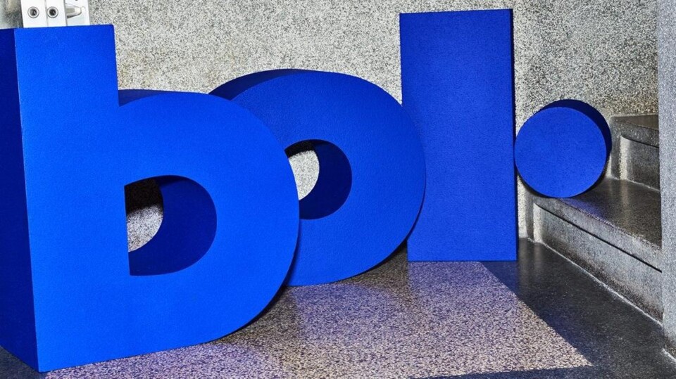 Blauwe 3D letters b, o, l en een punt op een grijze vloer en muur naast een trap.