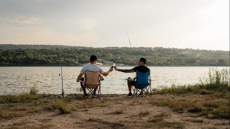 Twee mannen vissen langs een rivier.