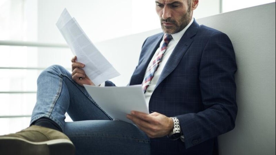 Een man bladert door een stapel vacatures.