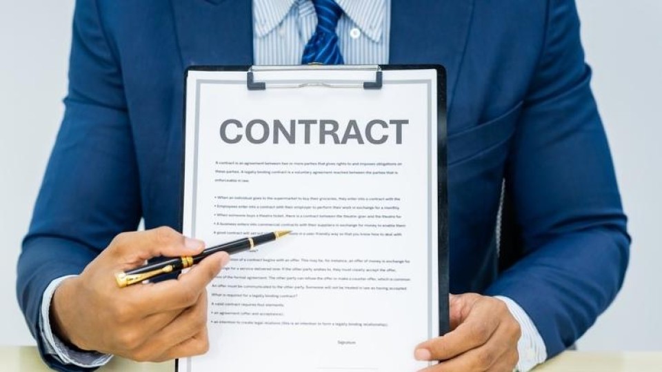 man houdt contract vast en wijst met pen daarop