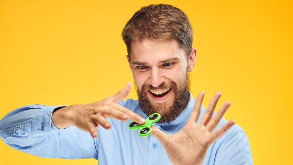 blij man die met fidget spinner speelt