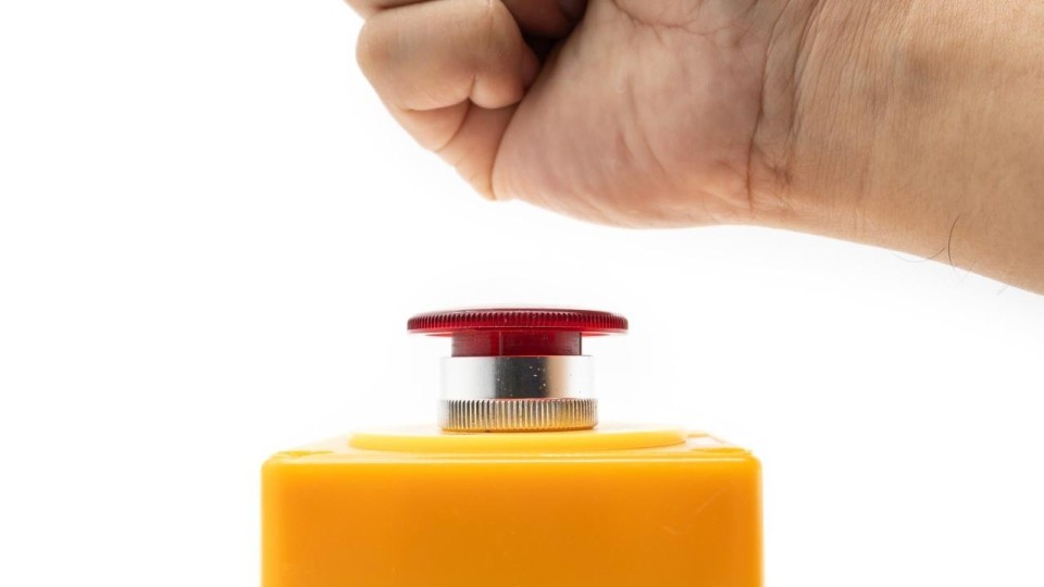 hand hangt boven stopknop