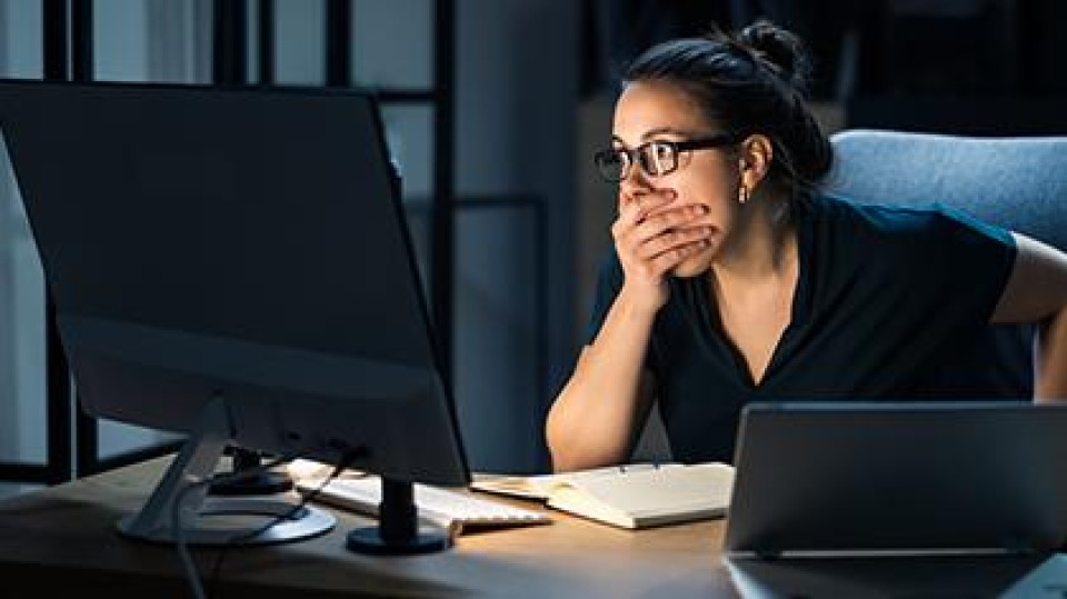 Vrouw schrikt terwijl ze kijkt naar haar beeldscherm