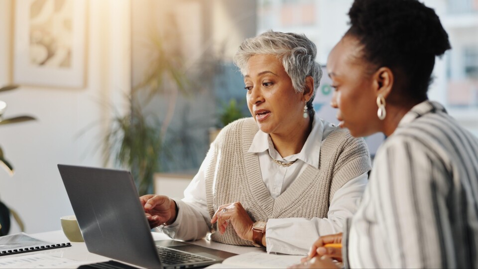 Twee vrouwen bespreken wat ze zien op een laptopscherm